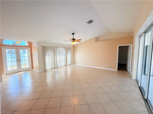 Spare room with french doors, a ceiling fan, lofted ceiling, and light tile patterned floors