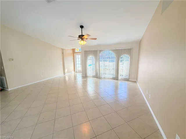 Empty room with a ceiling fan and light tile patterned floors