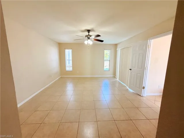 Empty room featuring a ceiling fan and light tile patterned floors