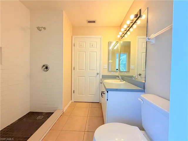 Bathroom featuring tiled shower, vanity, and light tile patterned floors