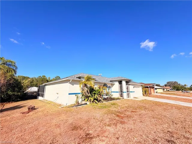 View of side of property featuring concrete driveway, an attached garage, stucco siding, and a yard