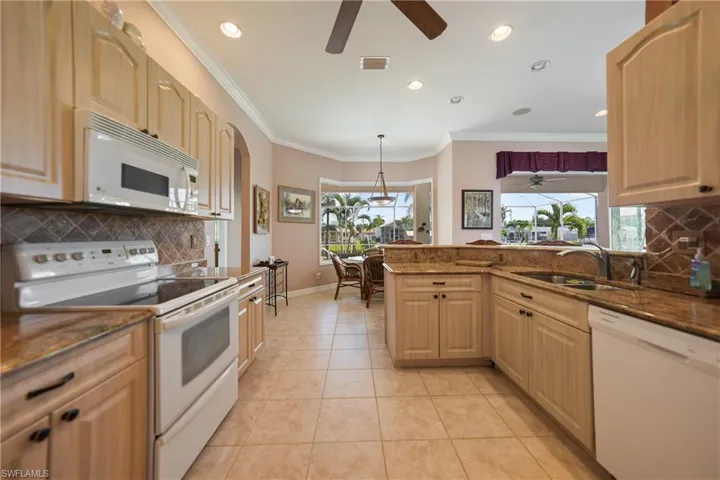 Kitchen featuring white appliances, sink, a wealth of natural light, backsplash, and ceiling fan