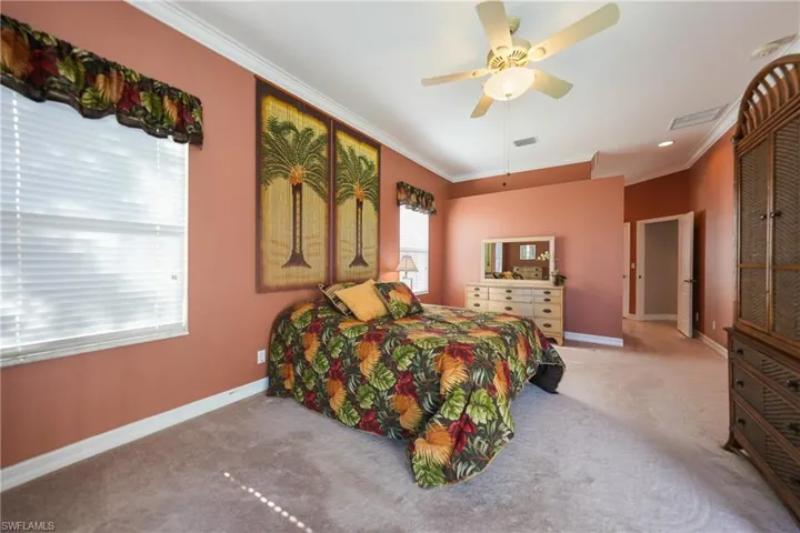 Bedroom featuring light carpet, crown molding, and ceiling fan