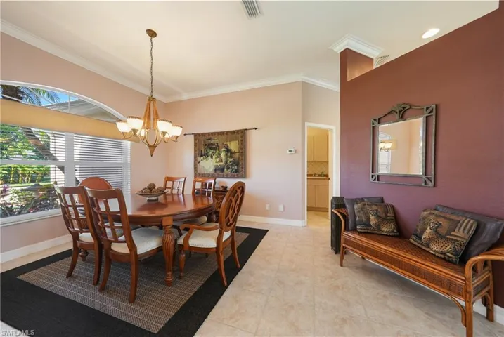 Tiled dining room featuring a notable chandelier and crown molding