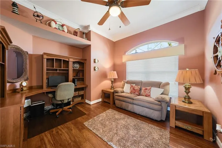 Office with dark wood-type flooring, crown molding, and ceiling fan