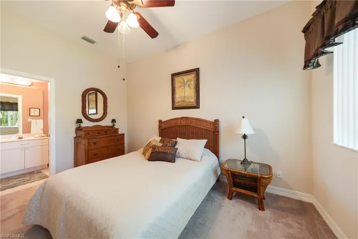 Bedroom featuring ceiling fan, connected bathroom, and light colored carpet