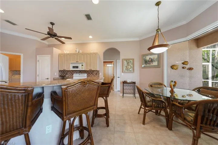 Kitchen with ornamental molding, tasteful backsplash, pendant lighting, and white appliances