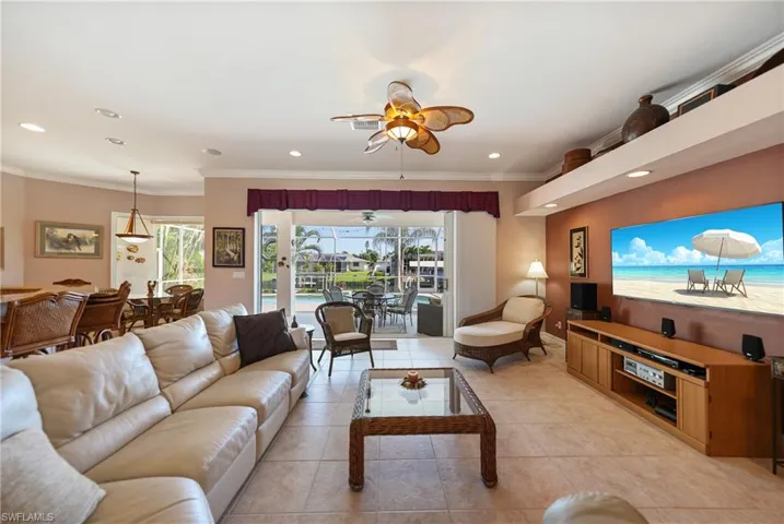 Living room with ornamental molding, light tile patterned floors, and ceiling fan