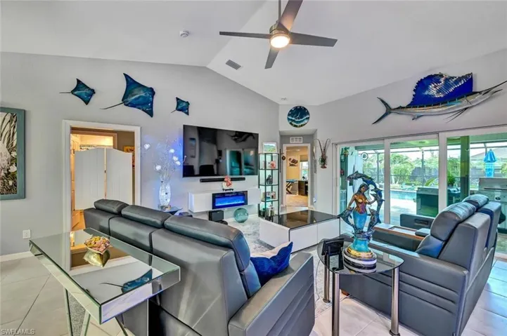 Spacious living area featuring vaulted ceilings, a ceiling fan, and tile flooring