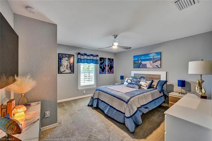 Carpeted room featuring a ceiling fan with integrated lighting, window with white plantation shutters, and light gray painted walls