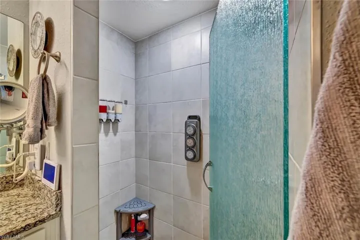 Shower enclosure featuring a frosted glass door, tiled walls, and a corner shelving unit