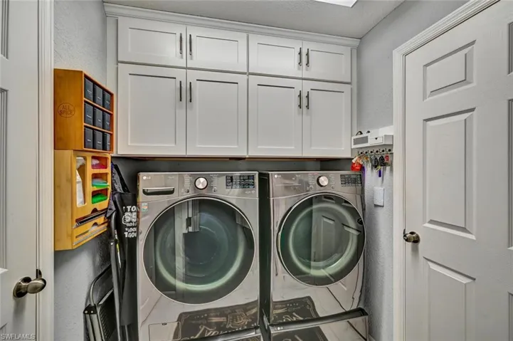 Laundry area featuring white shaker-style cabinetry with dark hardware and a built-in overhead light fixture