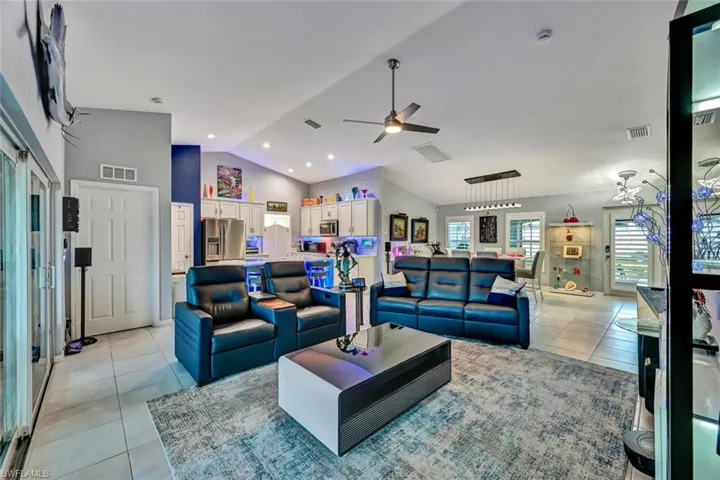 Expansive open-concept interior featuring vaulted ceilings, recessed lighting, and a neutral tile flooring throughout