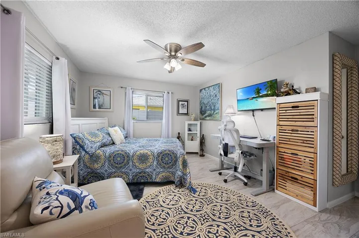 Bedroom with an office area, a textured ceiling, ceiling fan, and light wood-style floors