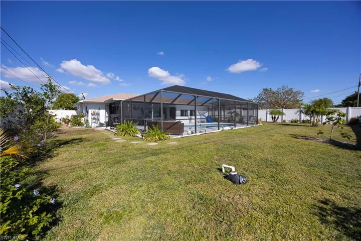 Fenced backyard featuring a sunroom and a lanai