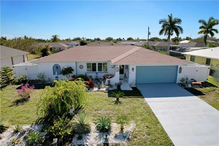 Ranch-style home with stucco siding, concrete driveway, roof with shingles, and a gate