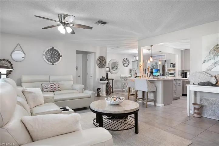 Living area featuring a textured ceiling, light tile patterned flooring, and ceiling fan
