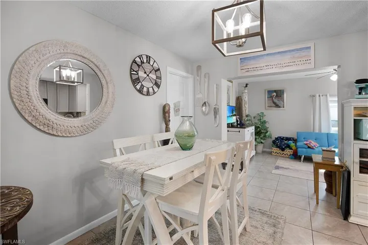 Dining area with a chandelier, light tile patterned floors, a textured ceiling, and ceiling fan