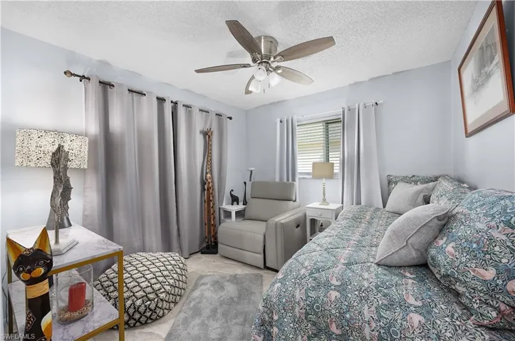 Bedroom with a textured ceiling, ceiling fan, and light carpet