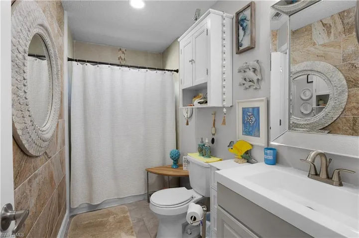 Full bath featuring vanity, a textured ceiling, and shower / bath combo with shower curtain
