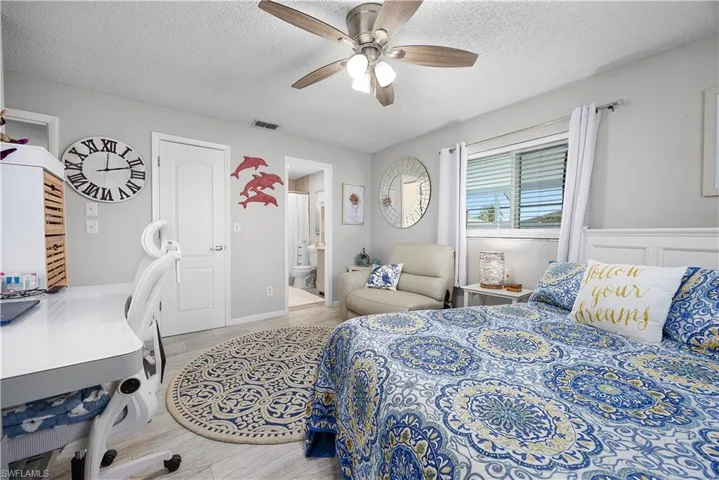 Bedroom featuring wood finish floors, a textured ceiling, a ceiling fan, and connected bathroom