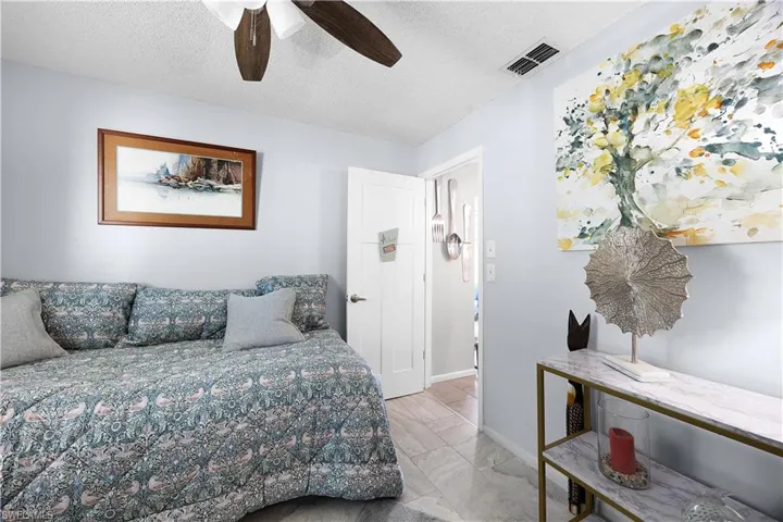 Bedroom with a textured ceiling, ceiling fan, and light marble finish flooring