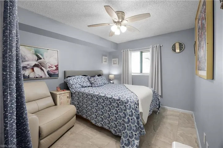 Bedroom with a ceiling fan and a textured ceiling