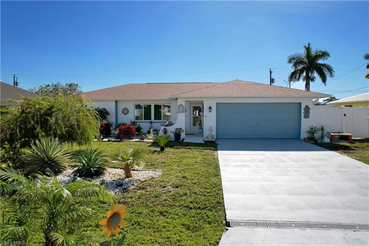Ranch-style home featuring concrete driveway, stucco siding, a garage, a front yard, and a gate