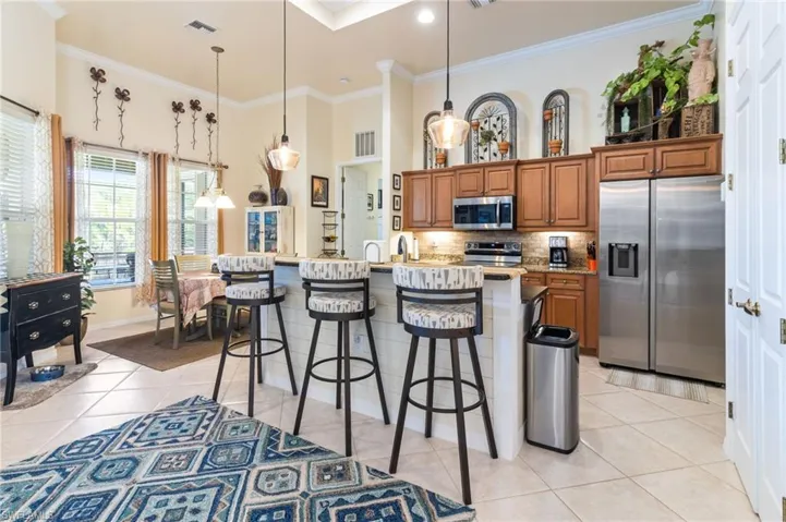 Kitchen featuring a kitchen breakfast bar, appliances with stainless steel finishes, an island with sink, pendant lighting, and tasteful backsplash