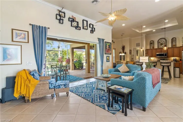Living room featuring light tile floors, ceiling fan, and a raised ceiling
