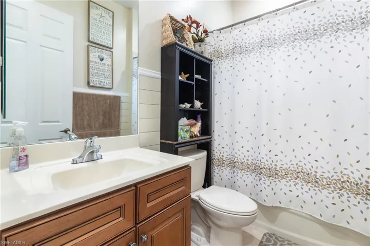 Full bathroom featuring shower / bathtub combination with curtain, toilet, and large vanity