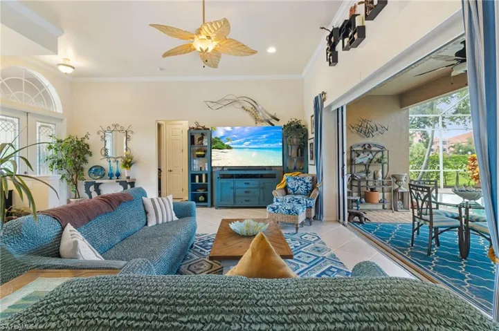 Tiled living room featuring ceiling fan, french doors, and crown molding