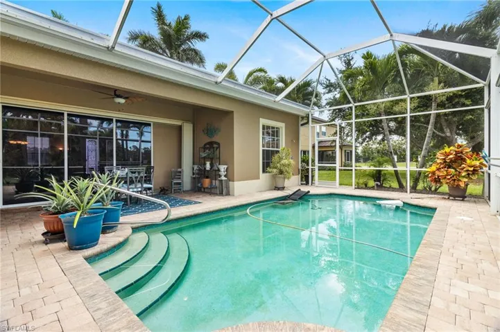 View of swimming pool featuring glass enclosure, a patio area, and ceiling fan
