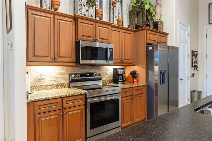 Kitchen featuring backsplash, appliances with stainless steel finishes, and stone counters