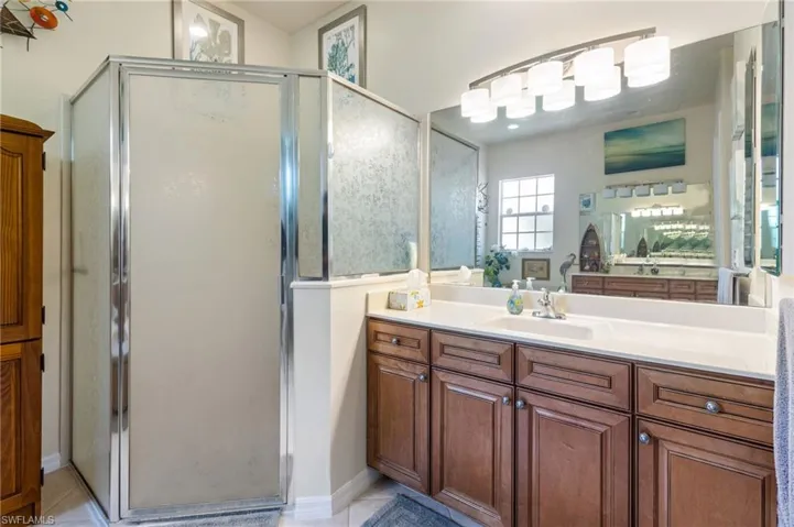 Bathroom with an enclosed shower, tile flooring, and vanity
