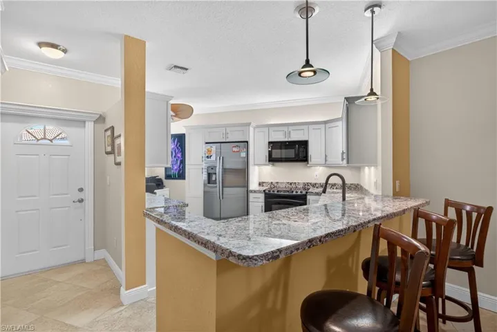 The kitchen features light-colored cabinetry, a stainless steel refrigerator, and a black range and microwave