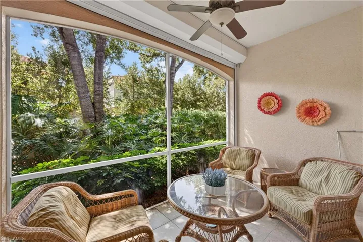 The property features a screened patio with tiled flooring, an outdoor ceiling fan, and a lush green view of surrounding trees and vegetation