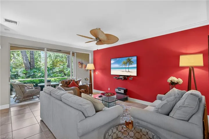 Living area featuring tile flooring, a vibrant accent wall, and a ceiling fan