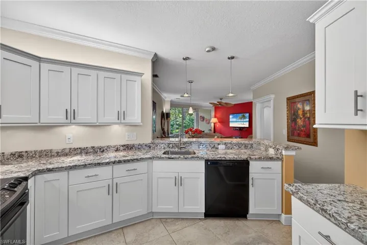 Kitchen with white cabinetry, speckled countertops, and a built-in dishwasher