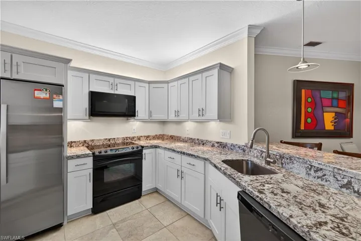 The kitchen features grey cabinetry, granite countertops, and stainless steel appliances including a refrigerator and a black range