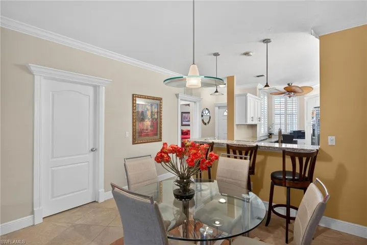 Dining area featuring crown molding, neutral wall colors, and a glass-top dining table with seating