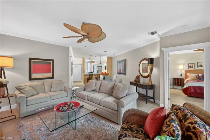 The living area features crown molding, a ceiling fan, and tile flooring, with a visible entryway leading to another room