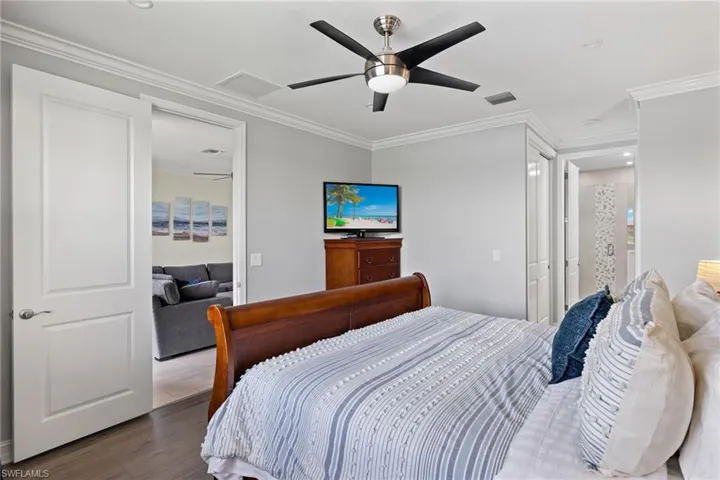 Bedroom with ceiling fan, ornamental molding, and hardwood / wood-style floors