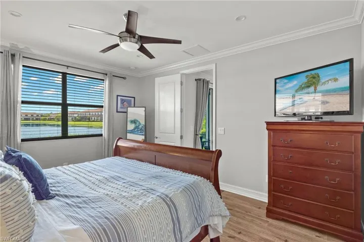 Bedroom with ornamental molding, ceiling fan, and light hardwood / wood-style flooring