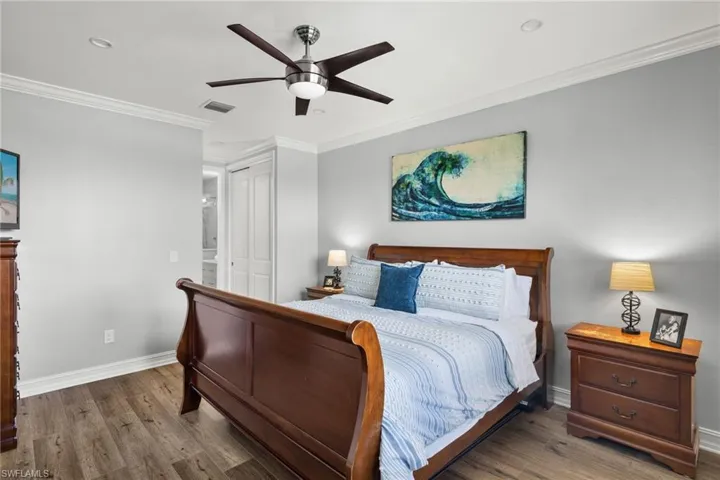 Bedroom with ceiling fan, a closet, ornamental molding, and wood-type flooring