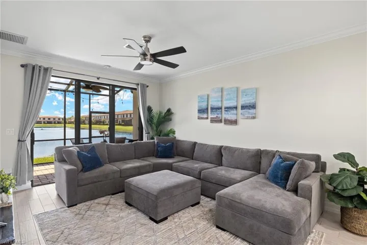 Living room featuring a water view, light hardwood / wood-style floors, ceiling fan, and crown molding