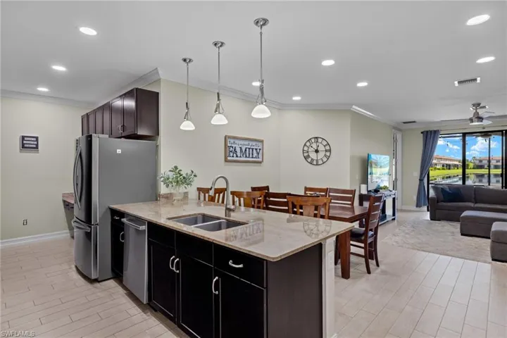 Kitchen featuring sink, hanging light fixtures, stainless steel appliances, ornamental molding, and ceiling fan
