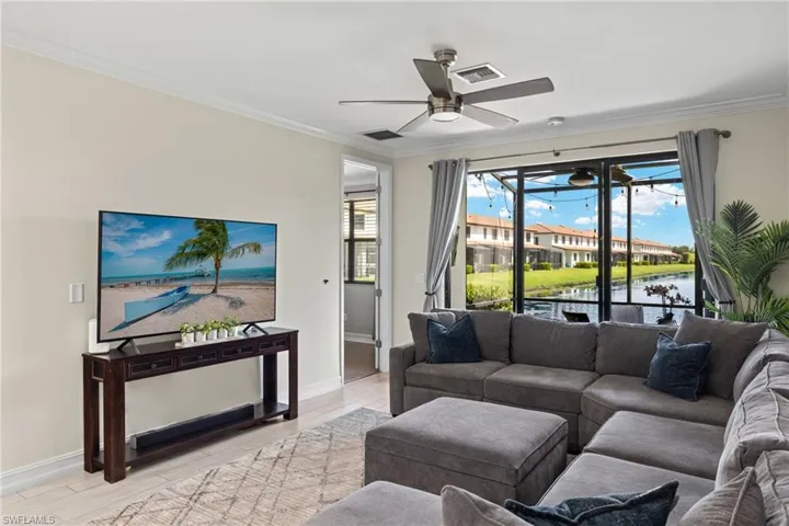 Living room featuring light wood-type flooring, crown molding, a water view, and ceiling fan