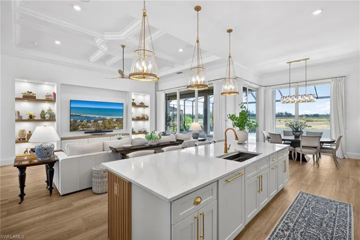 Kitchen with a chandelier, light stone counters, an island with sink, light wood finished floors, and open floor plan
