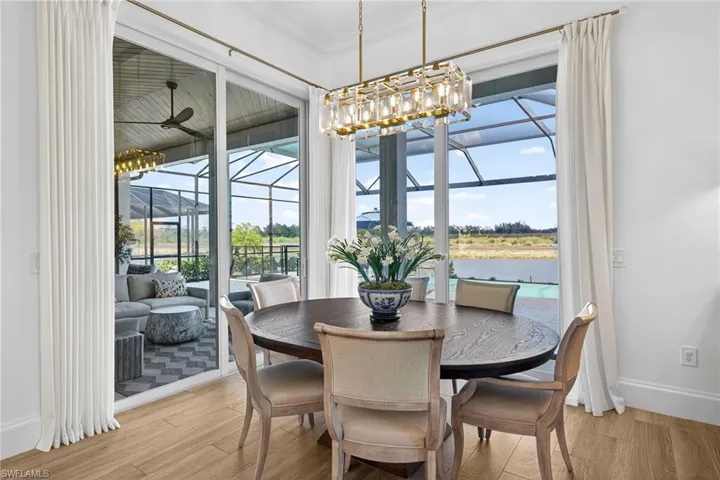 Dining space featuring a sunroom, light wood-style floors, ornamental molding, a ceiling fan, and a water view